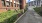 a road with bushes and buildings on the side